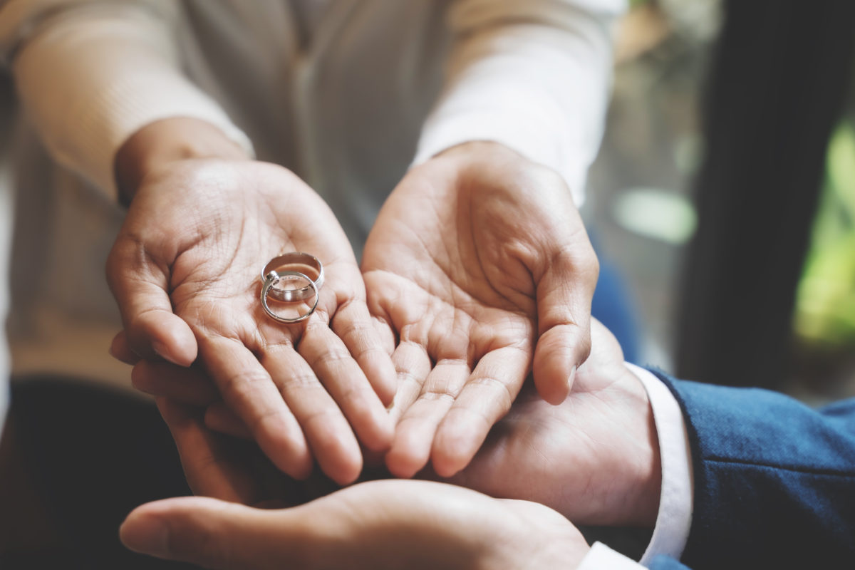 A woman's hands handing back her engagment and wedding band to a man; Broward County Divorce Lawyer concept image