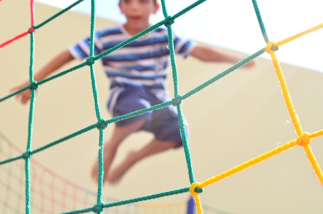 child jumping behind colorful netting