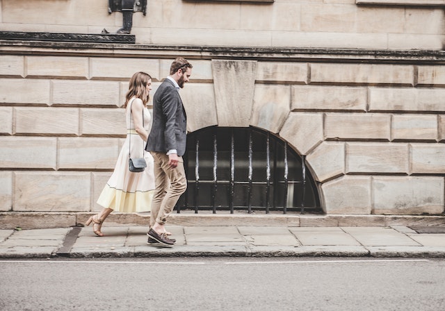 two people walking on a sidewalk