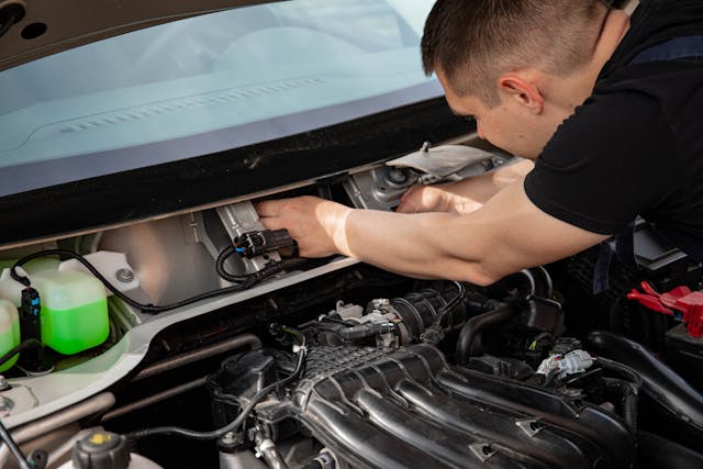 man working in car engine