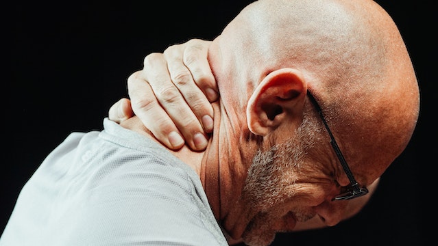 man grabbing back of neck in pain