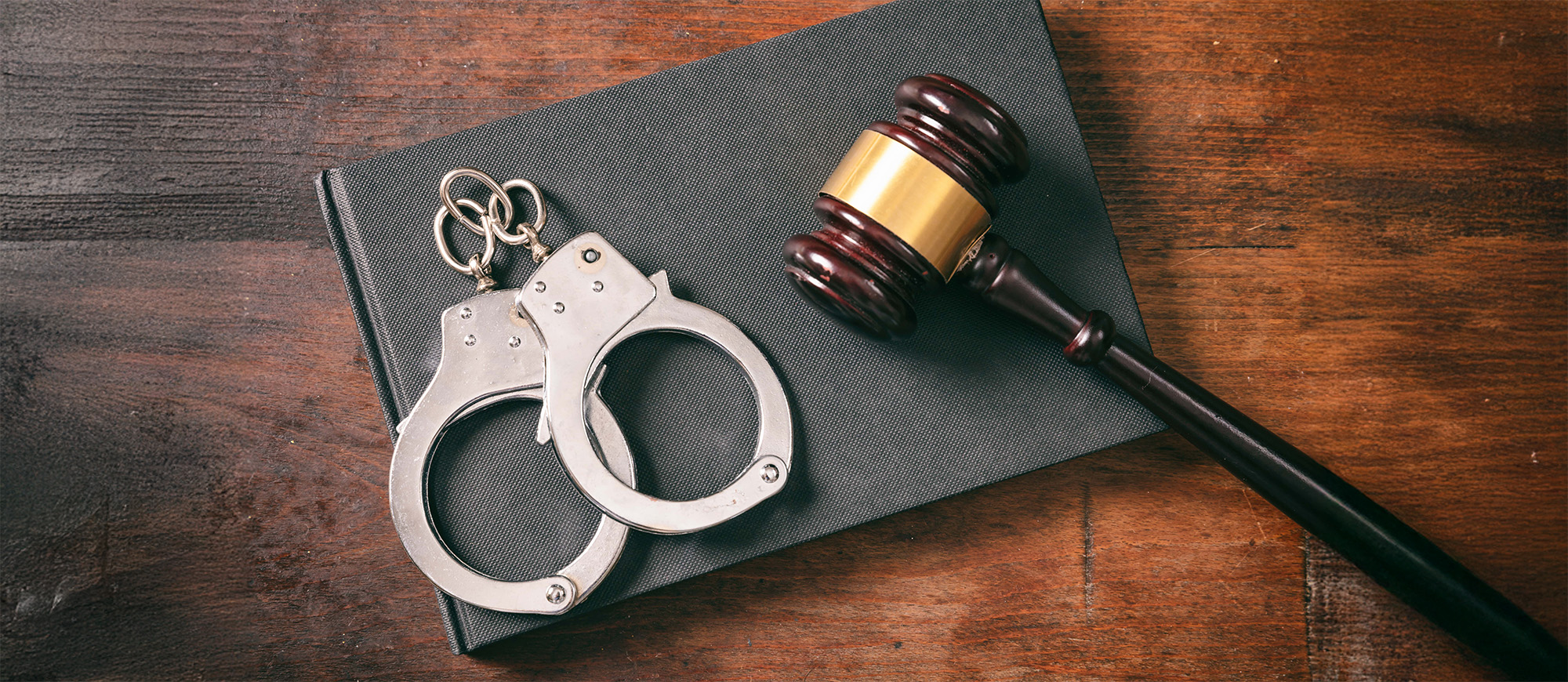 Handcuffs gavel on book on a wooden background