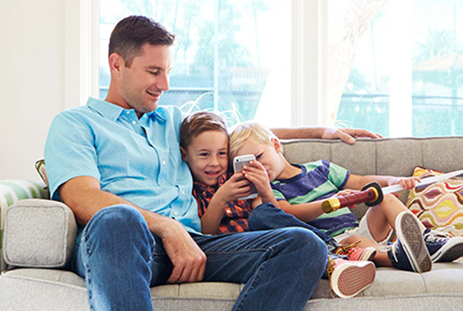 Man sitting on sofa with kids using smart phone