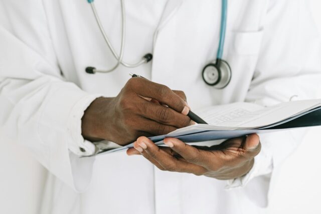doctor writing on clipboard