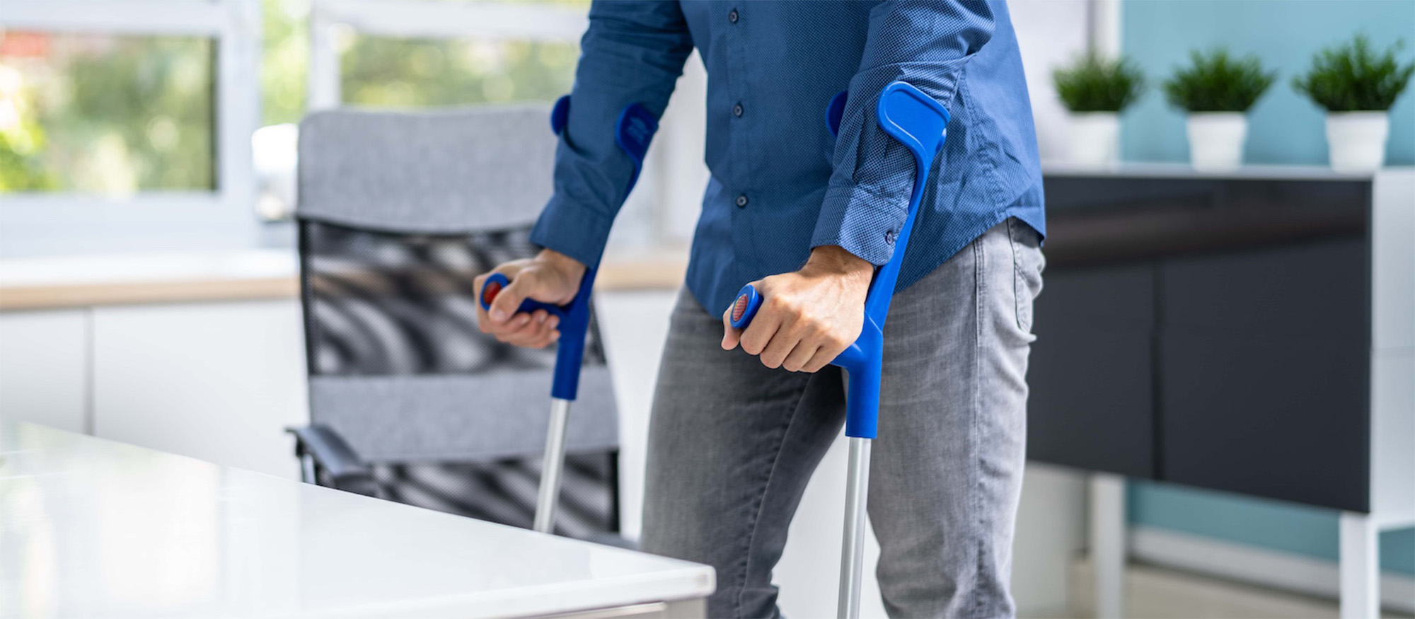 worker with crutches at workplace or office